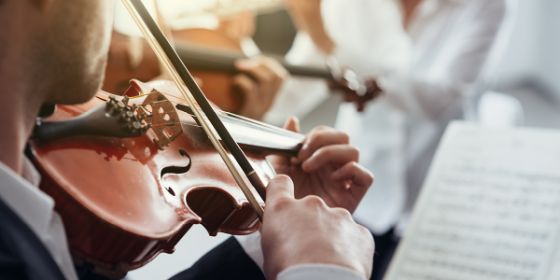 Fotografía de un músico tocando el violín en una orquesta