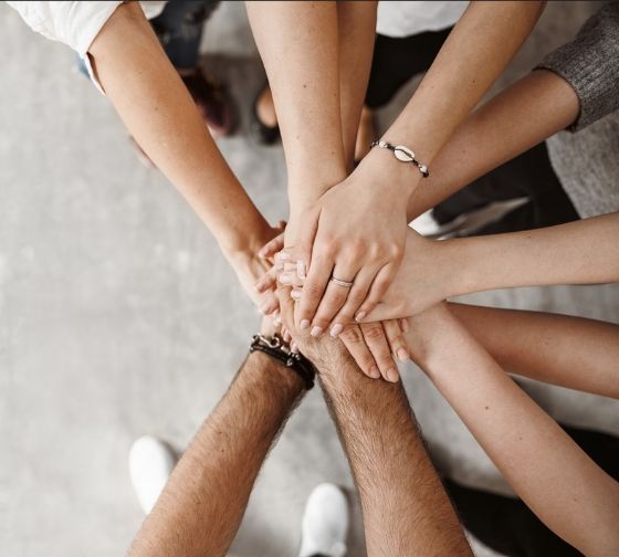 Manos juntas de distintas personas formando equipo