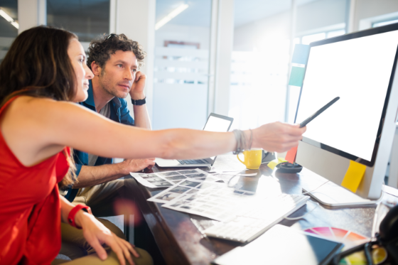 Fotografia de mujer y hombre trabajando juntos frente a una pantalla de ordenador