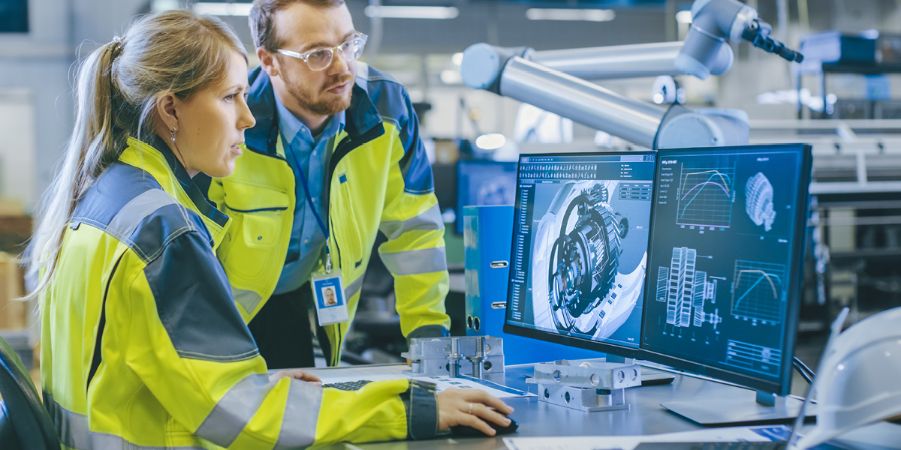 Dos trabajadores, una mujer y un hombre, frente a dos pantallas de ordenador.