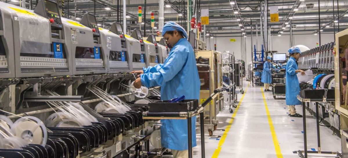 Trabajadoras en una factoría. Tres mujeres a distintas distancias vestidas con ropas y gorros azules trabajando con máquinas modernas.