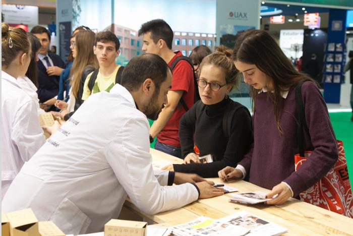 Imagen de dos chicas recibiendo información en un stand de la feria